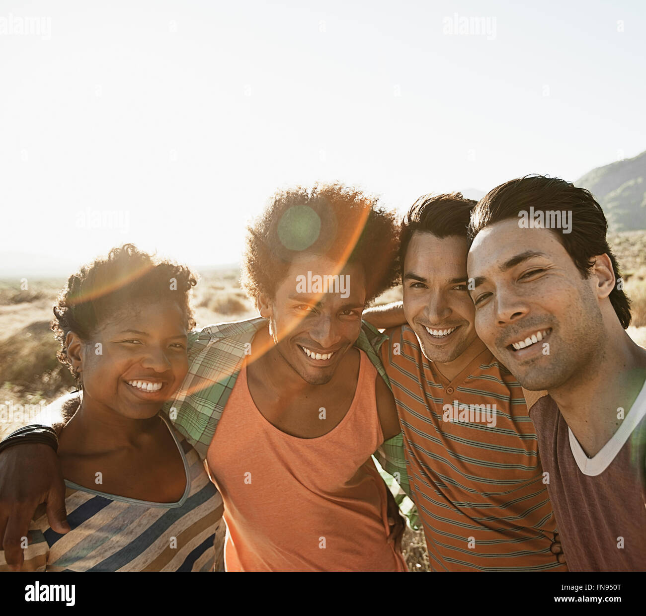 A group of friends, men and women, heads together posing for a selfy in the heat of the day. Stock Photo