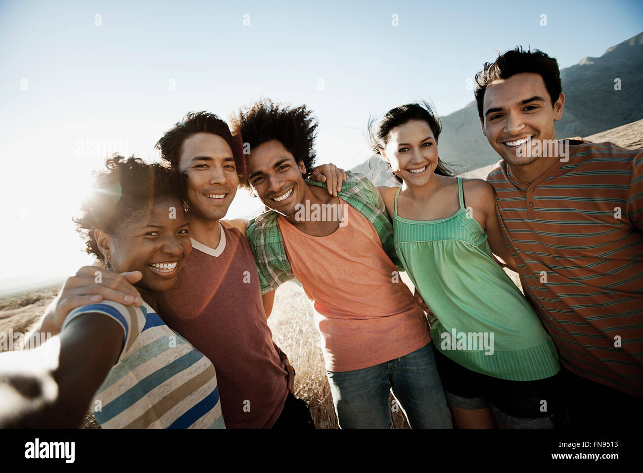 A group of friends, men and women, heads together posing for a selfy in the heat of the day. Stock Photo