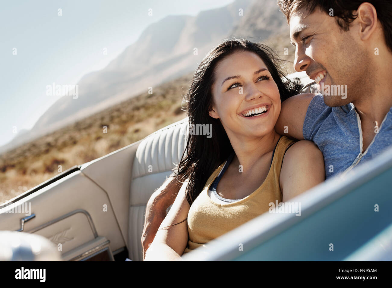 A young couple, man and woman in a pale blue convertible on the open road Stock Photo