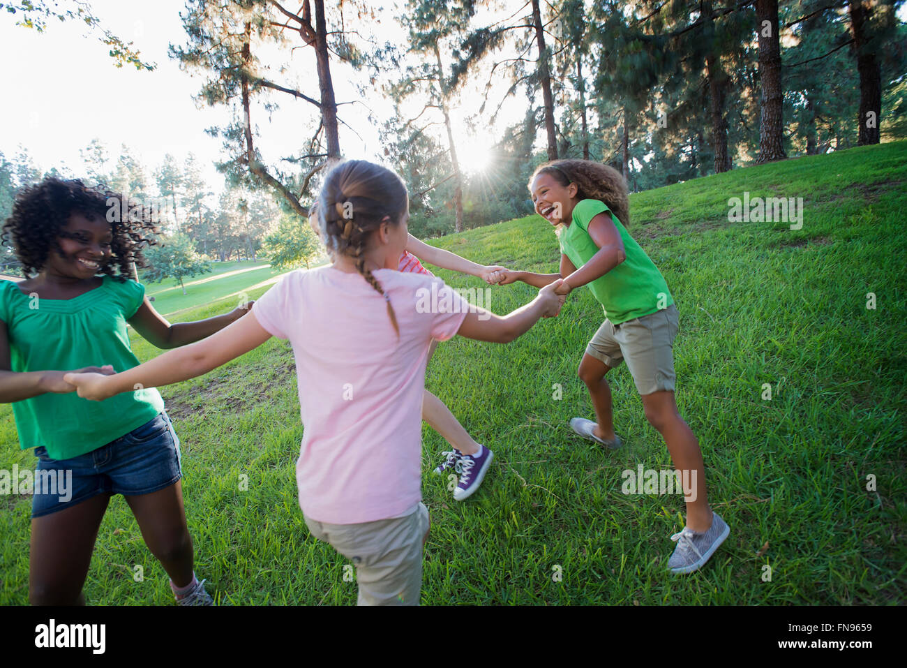 A group of four girls holding hands and dancing outside. Stock Photo