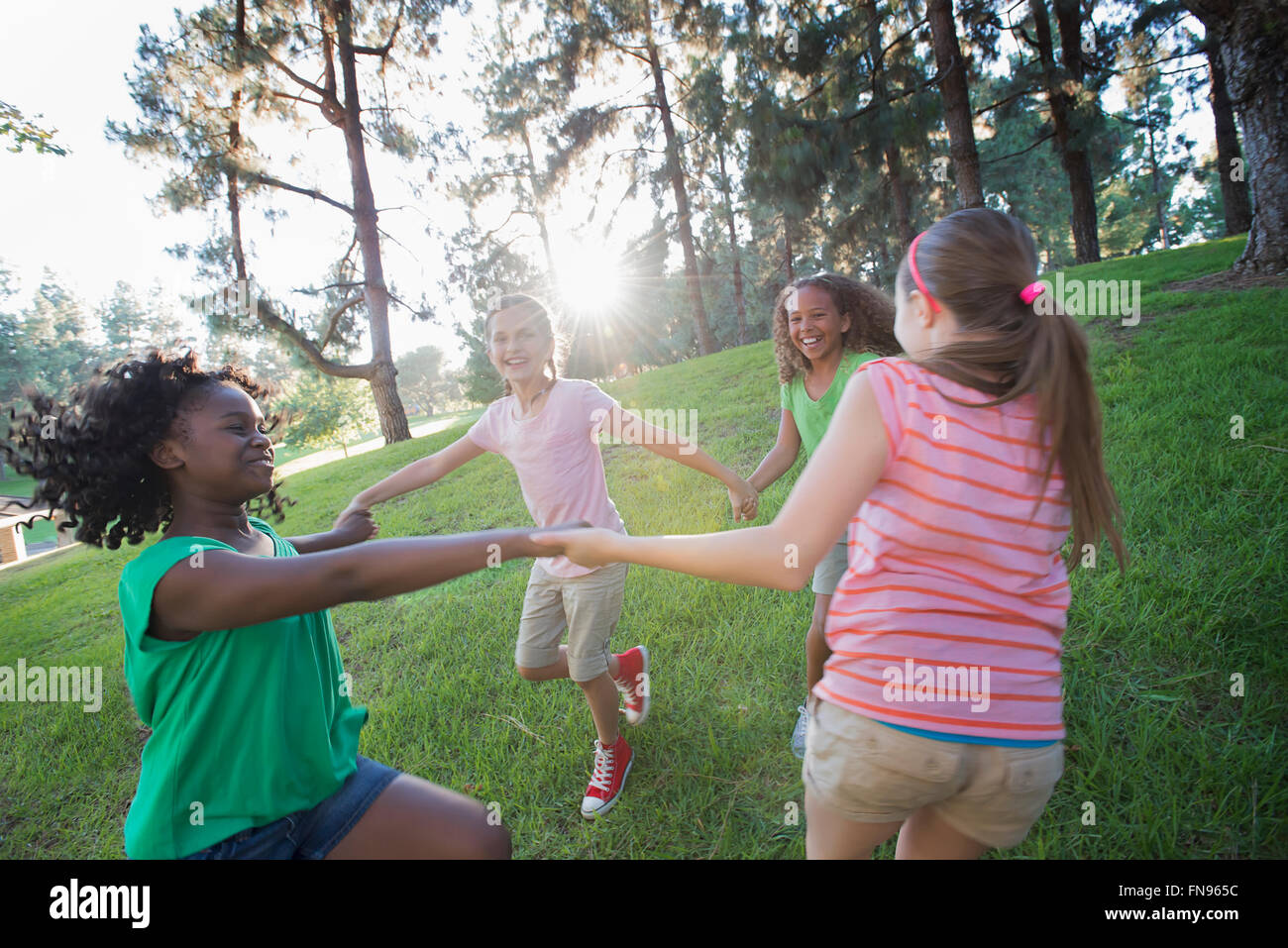 A group of four girls holding hands and dancing outside. Stock Photo