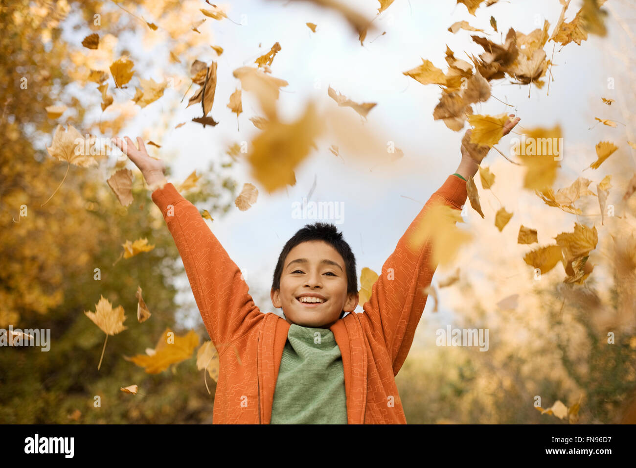 A boy throwing handfuls of fallen autumn leaves in the air Stock Photo