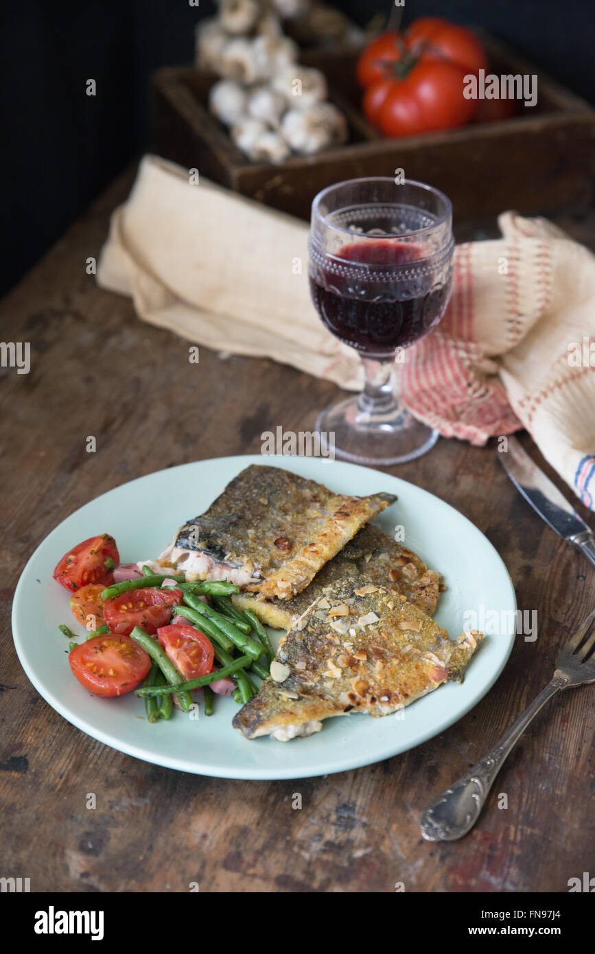 Fish with tomato, green beans and a glass of red wine Stock Photo
