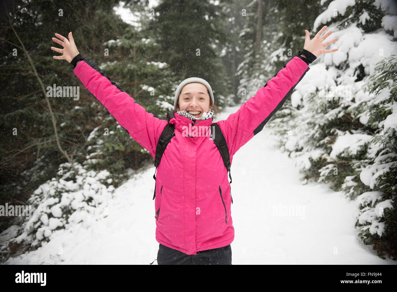 Woman standing in snow with arms in the air Stock Photo