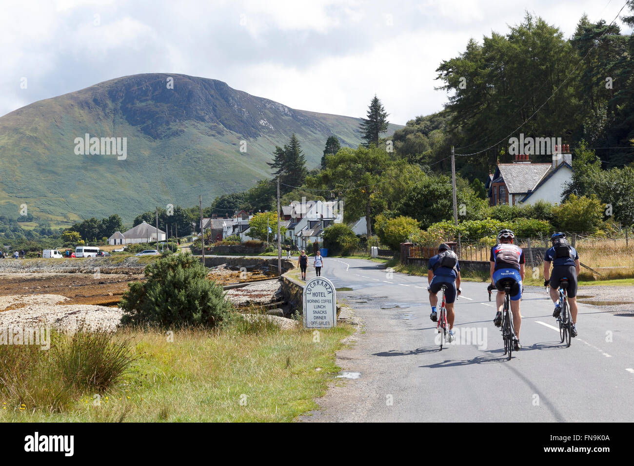 Three cyclists entering Lochranza, a village on the picturesque Isle of Arran, Scotland Stock Photo