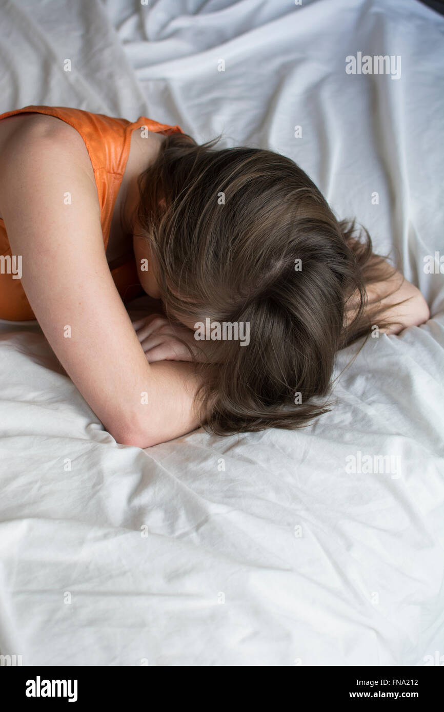Depressed young woman head in hands in bed Stock Photo