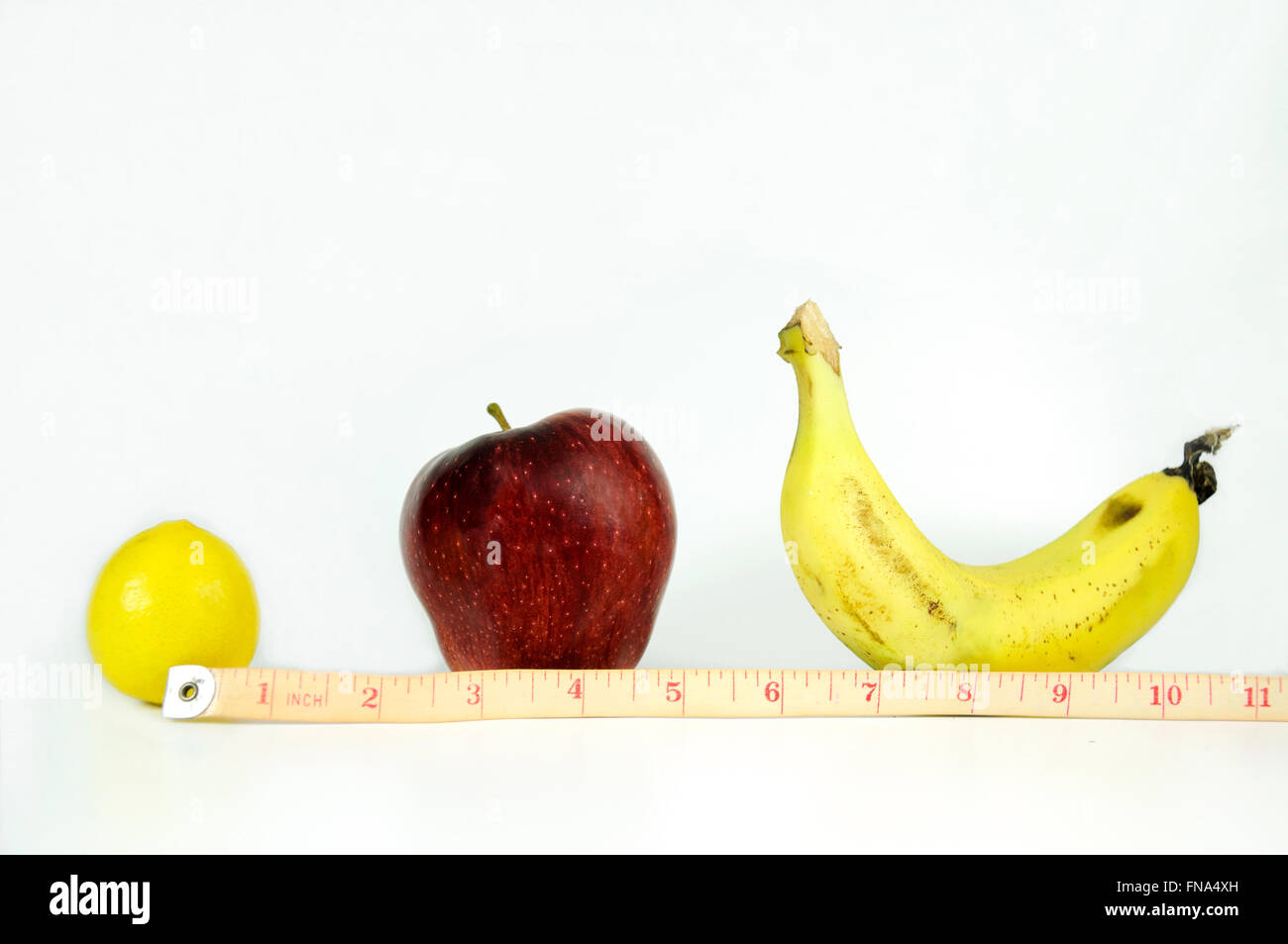 Measuring tape showing inches is wrapped around a lemon, apple, banana ...