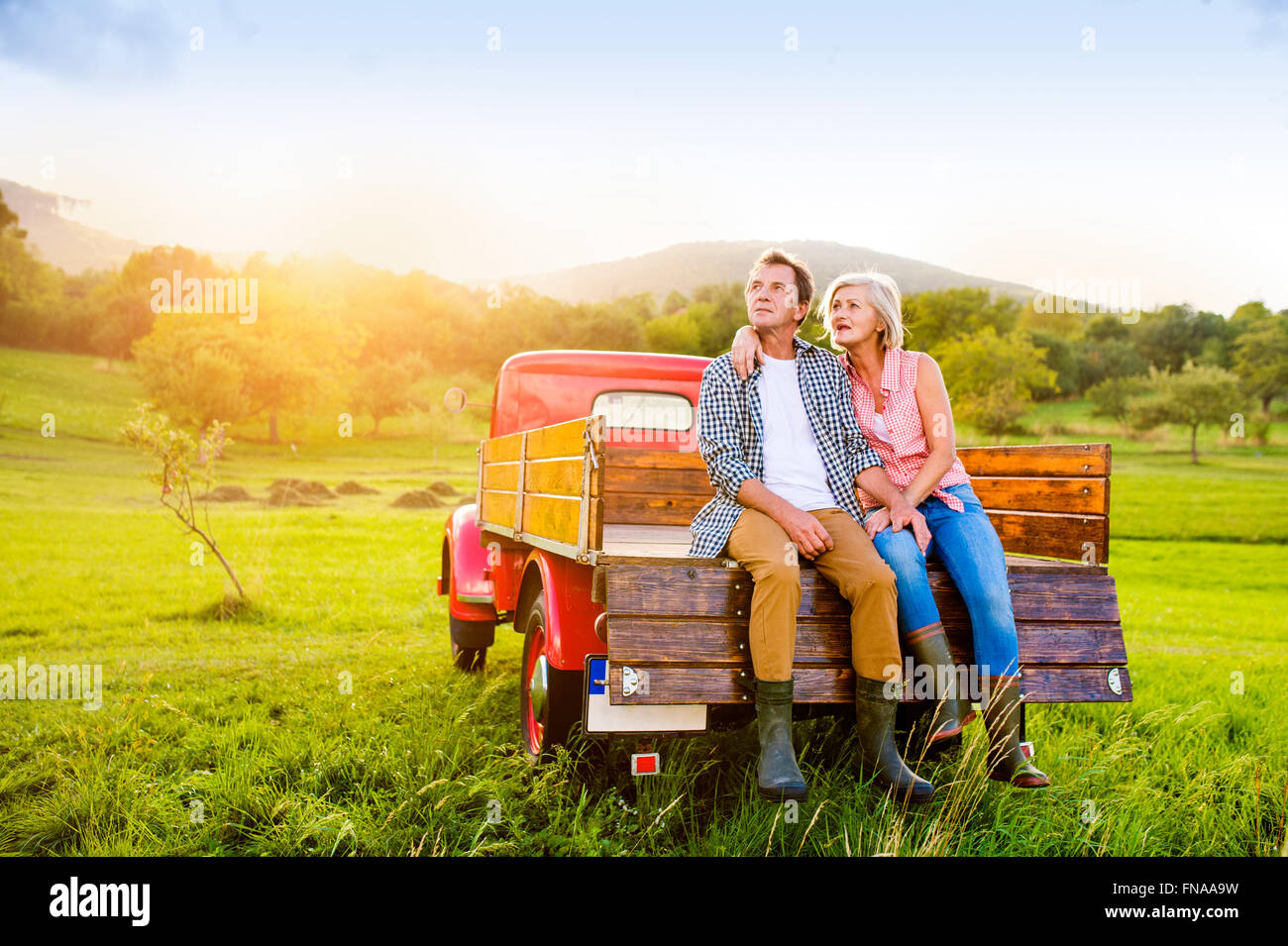 Senior couple sitting in back of red pickup truck Stock Photo