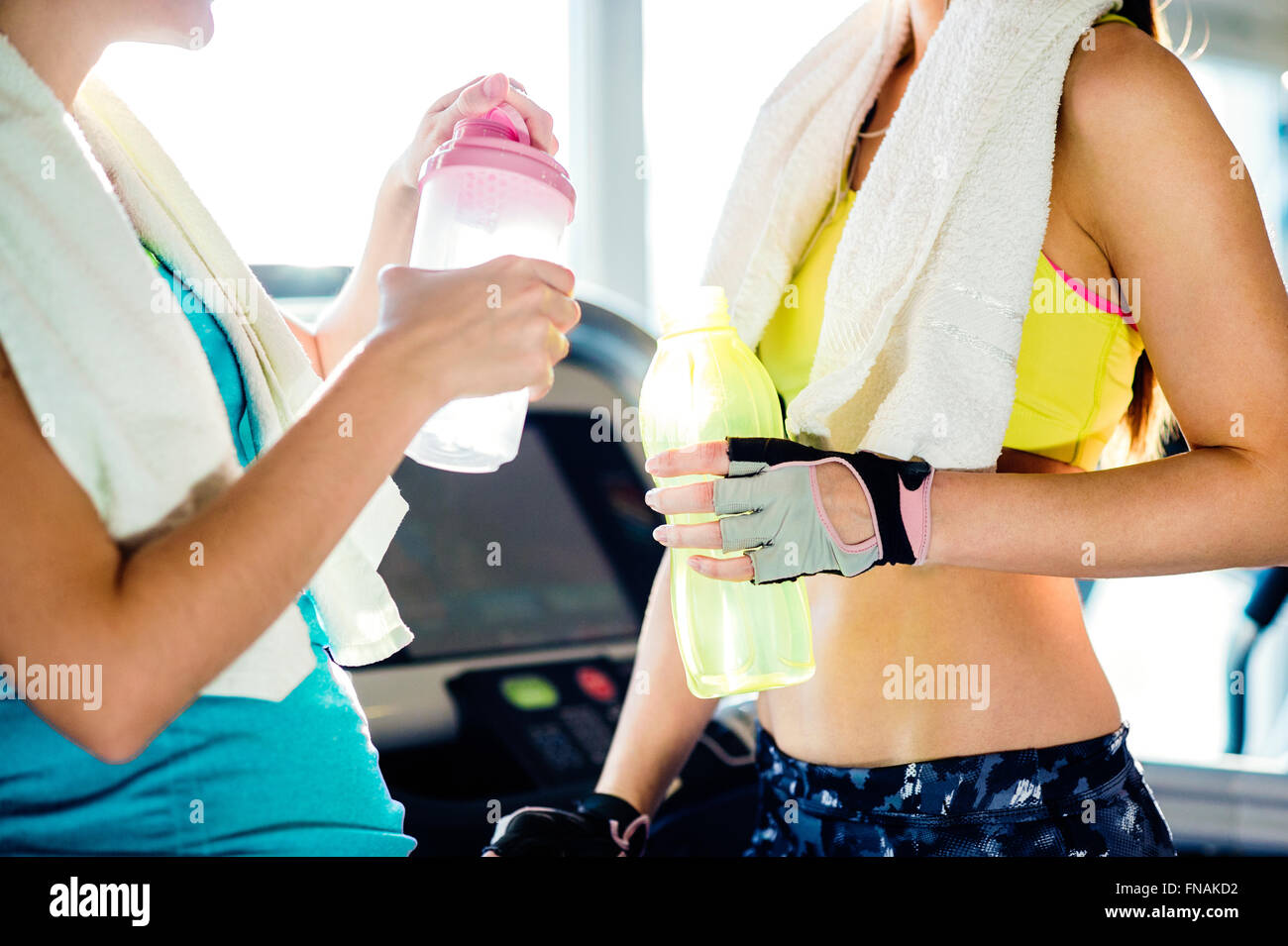 Two women in gym with water bottles and towels Stock Photo - Alamy