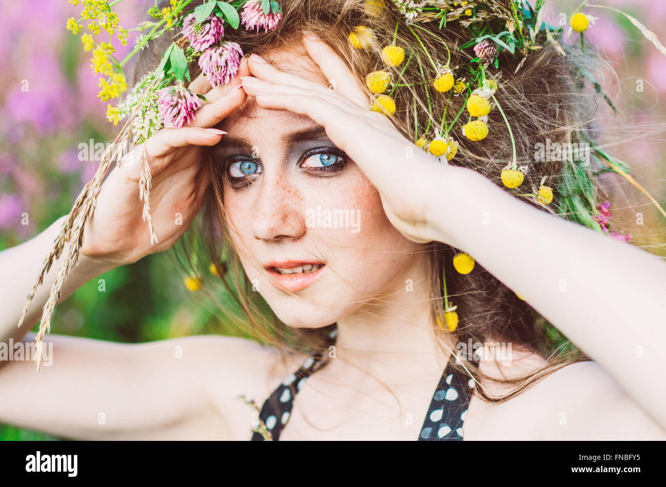 Portrait of smiling young girl with closed eyes in willow-herb field ...