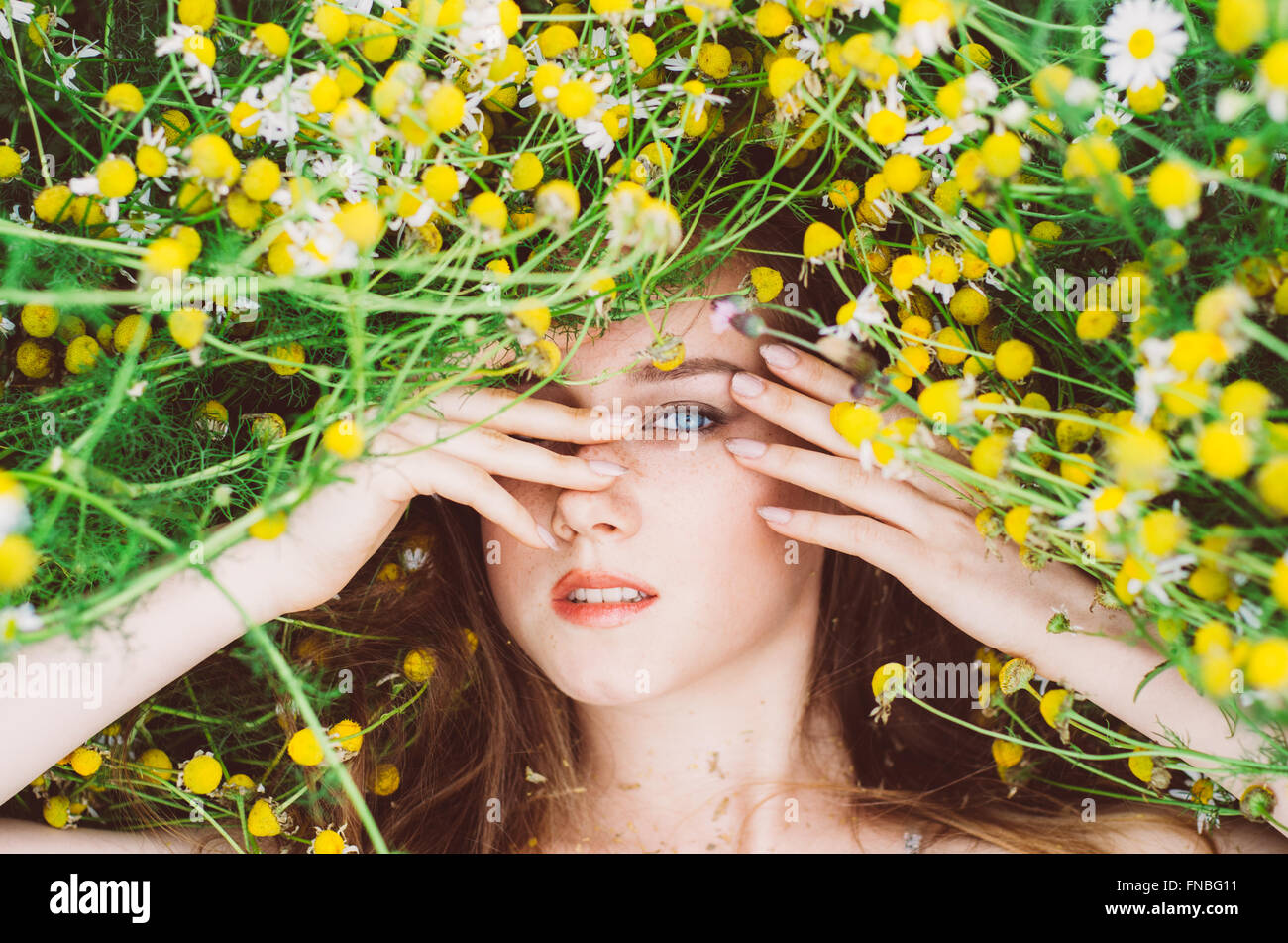 Portrait of young girl with blue eyes and freckles in chamomile field ...