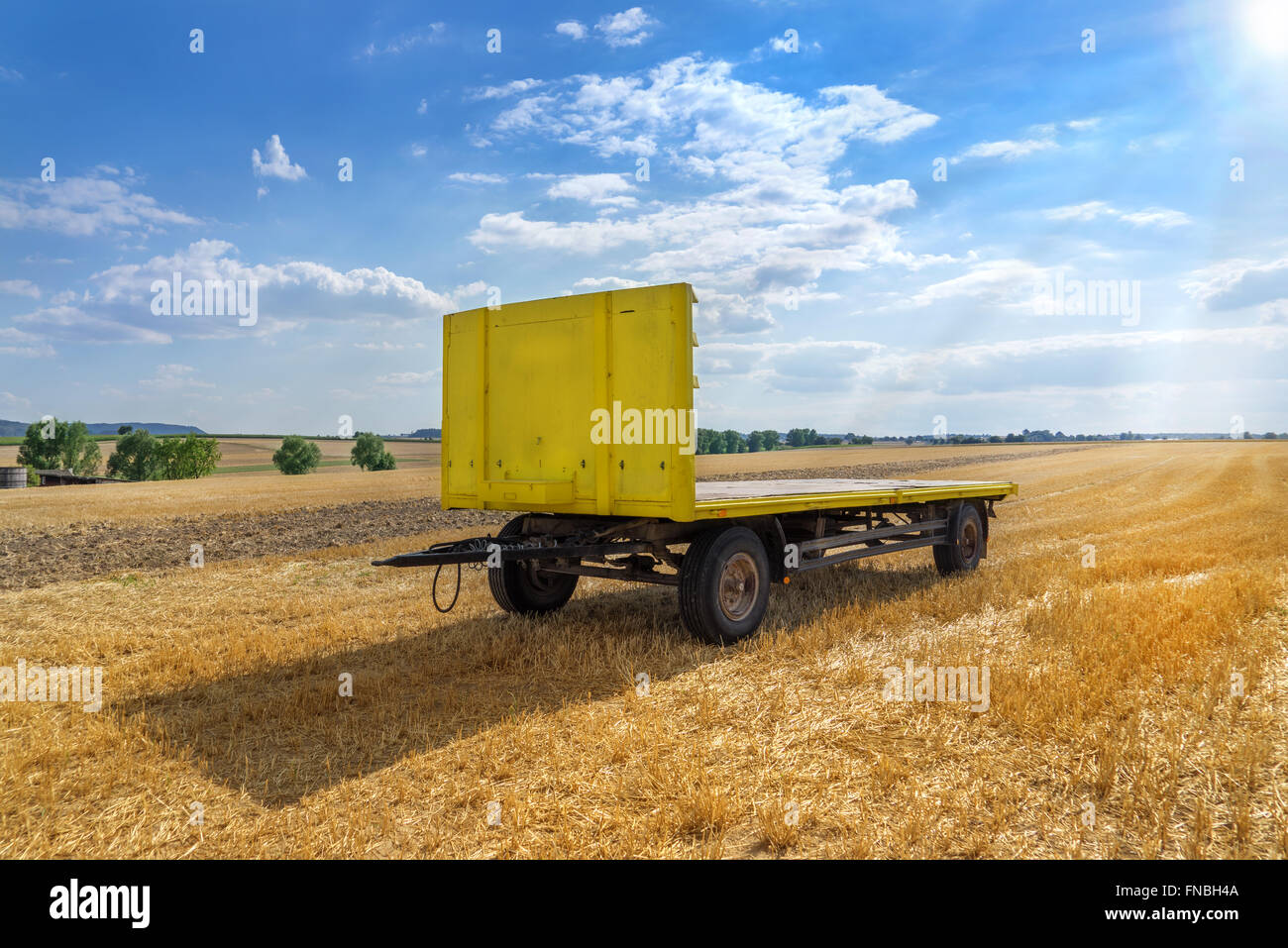 Big yellow trailer with open loading area in a stubble field in rural landscape Stock Photo