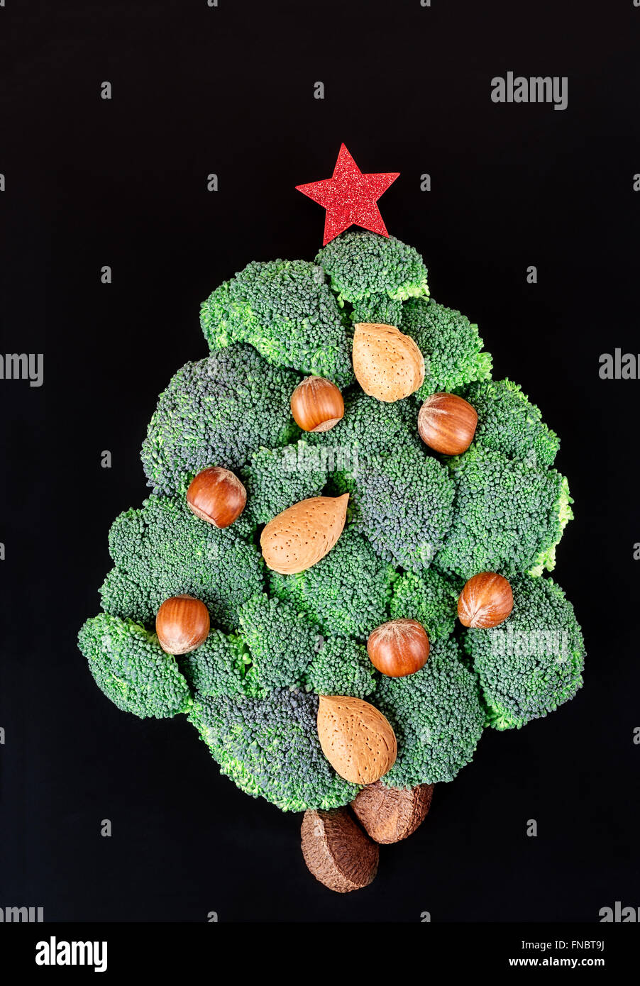 Christmas tree decoration made of broccoli flowerheads and decorated with nuts. Stock Photo