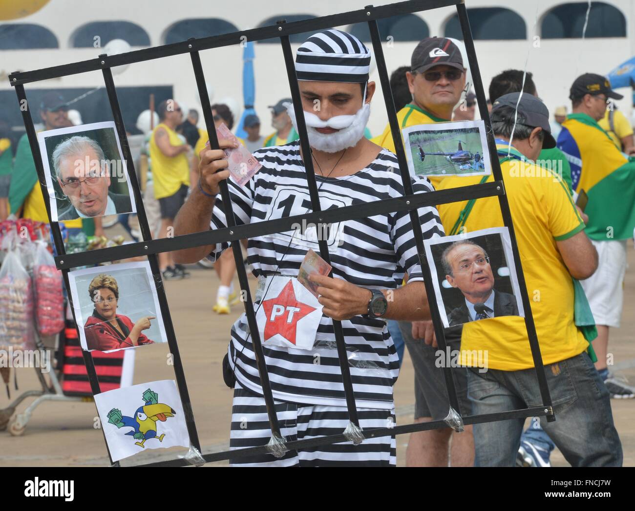 Brasilia, Brazil. 13th Mar, 2016. A protester wearing prisoner stripes joins thousands gathered outside the government district in the capital to demand the resignation of Brazilian President Dilma Rousseff March 13, 2016 in Brasilia, Brazil. Rousseff rejected calls for her resignation amidst a political storm deepened by a massive corruption scandal. Stock Photo