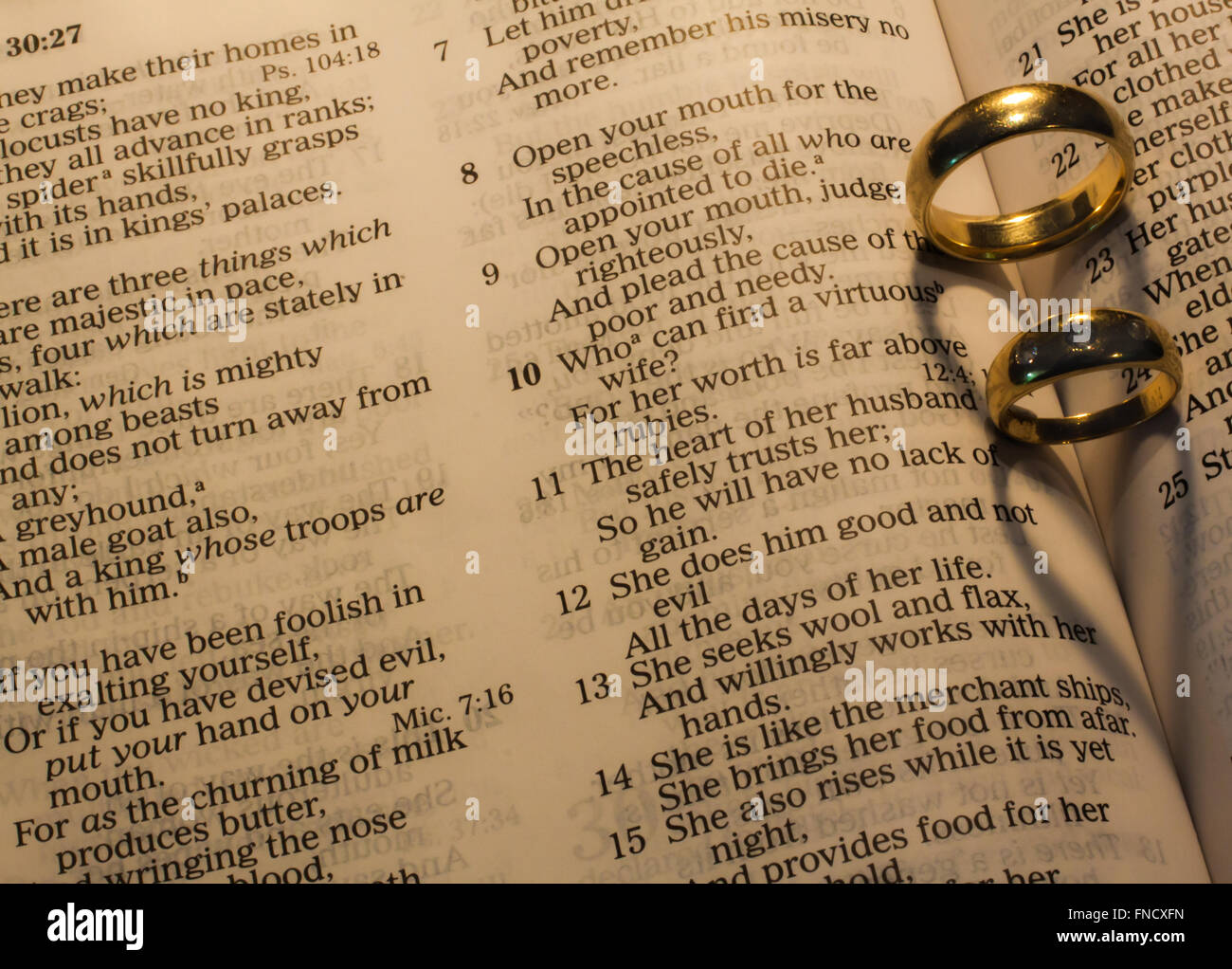 wedding rings making heart shaped shadows on bible pages Stock Photo