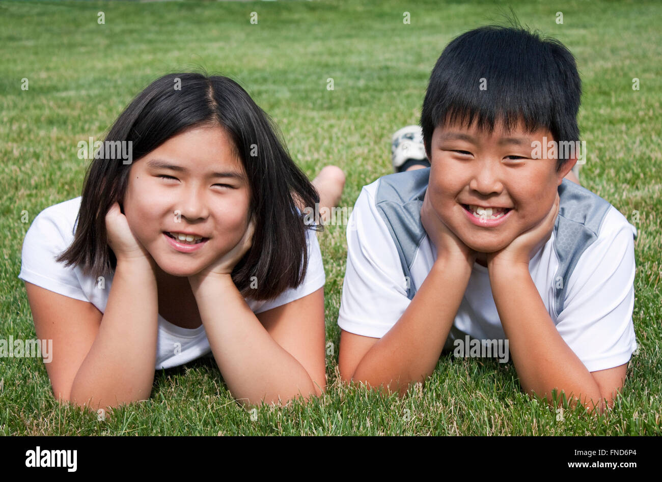 Brother and sister laying in the grass Stock Photo