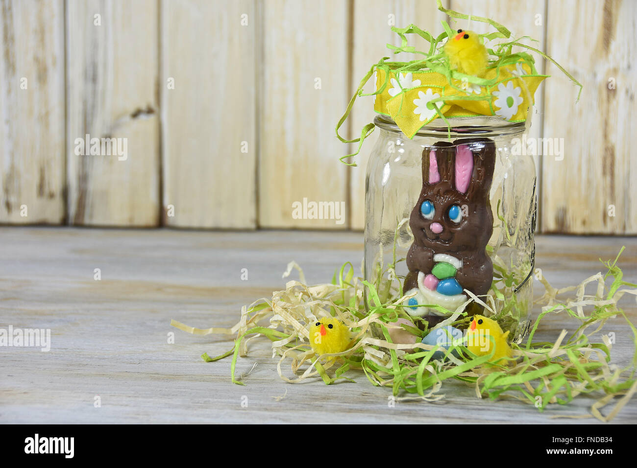 Chocolate Easter bunny in glass mason jar with yellow chicks in grass Stock Photo Alamy