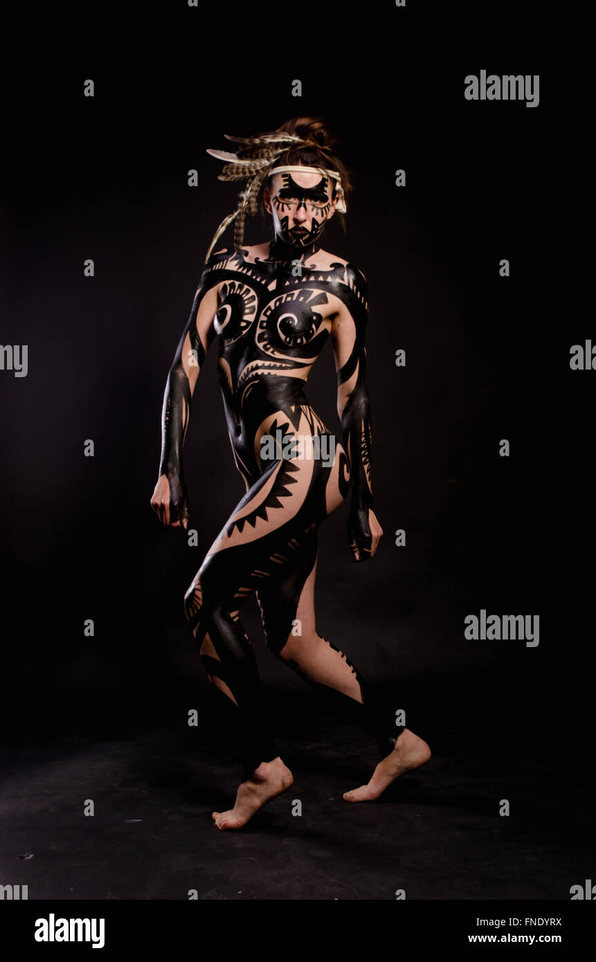 girl painted with black paint in the image of warrior women on a black background Stock Photo