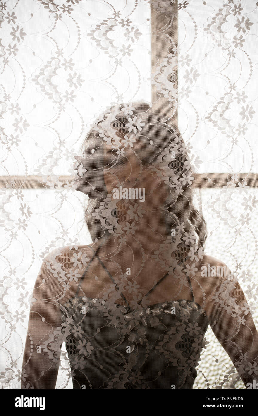 Beautiful Indian woman standing behind the blinds Stock Photo