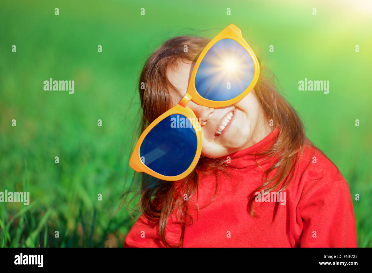 Happy little girl with big sunglasses in the meadow Stock Photo