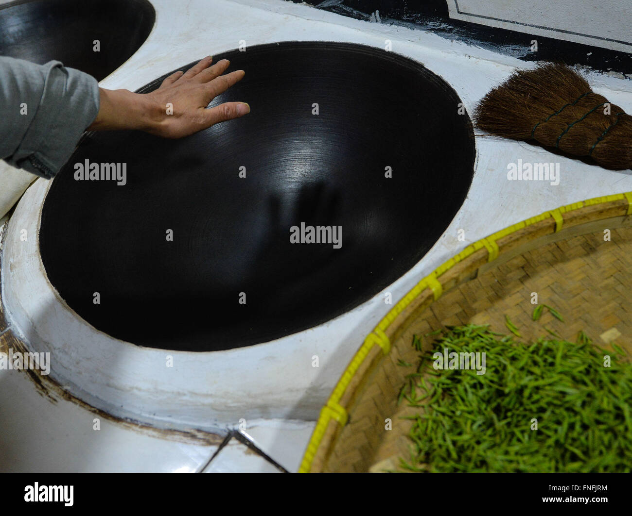 (160315) -- SUZHOU, March 15, 2016 (Xinhua) -- Yan Jielong feels the temperature of pot before baking Biluochun tea in Dongshan Town, Suzhou City of east China's Jiangsu Province, March 14, 2016. Yan Jielong, 53 years old, inheritor of ancient making technique of Chinese tea Biluochun, has learnt the skill since he was 16 years old. Requiring high standard of making technique, Biluochun tea is the speciality of Dongshan Town, where the people who know the ancient making technique are mostly in their 50s. Yan and other inheritors have taken video of their method and hope they may someday open a Stock Photo