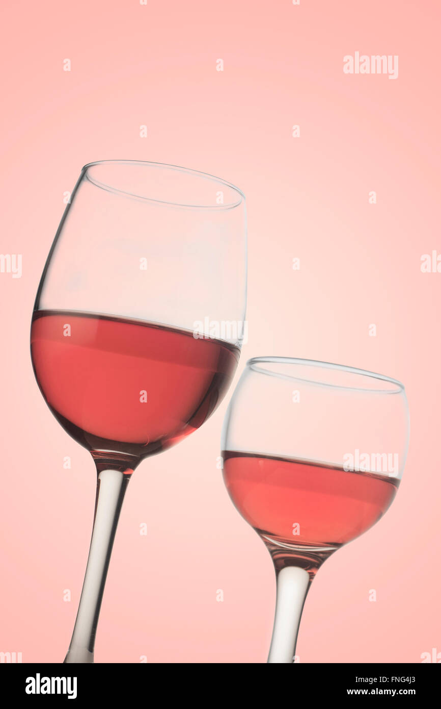 Vertical front view of two rose wine glasses isolated on pink