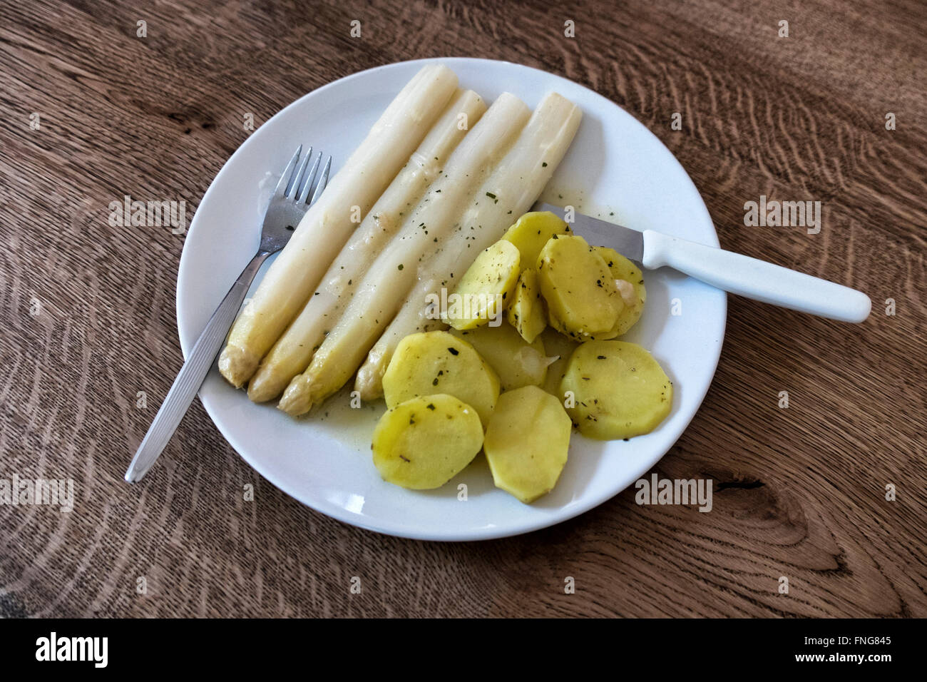 Fresh seasonal asparagus and herbed potatoes. Favourite German meal in Spring. Stock Photo