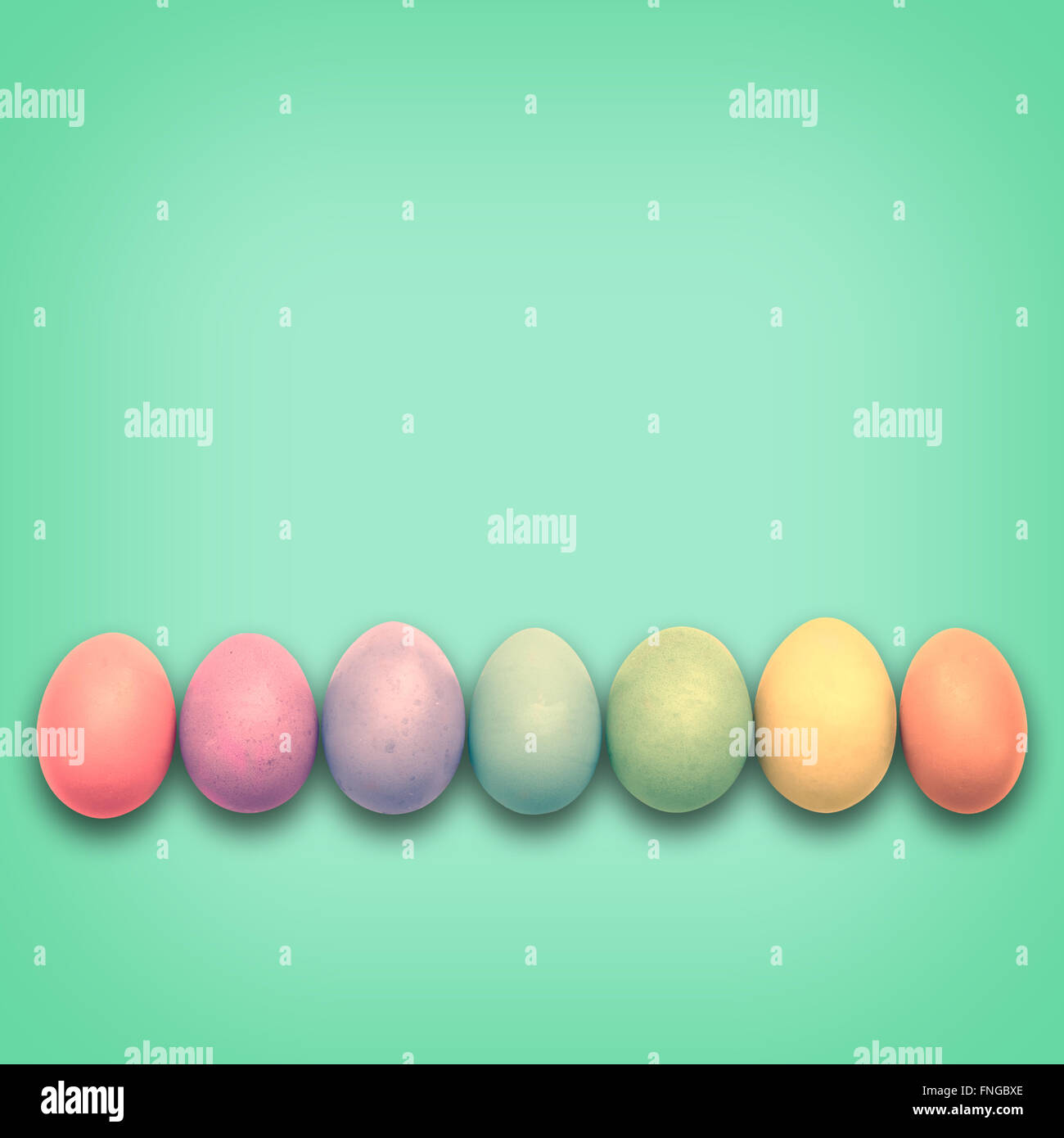 Pastel Easter eggs aligned, green background Stock Photo