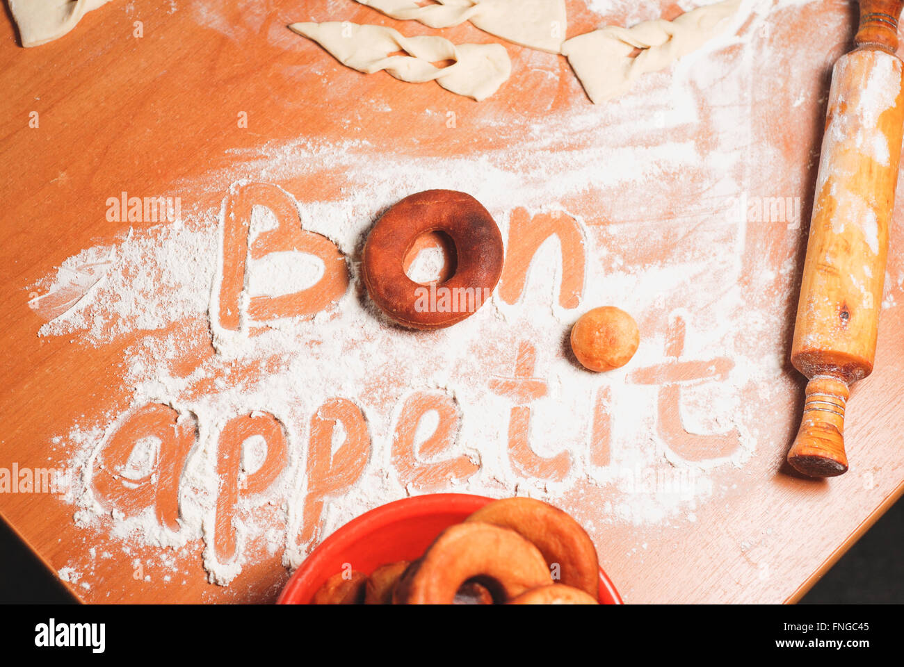 The inscription bon appetit on the table with flour , dough and donuts