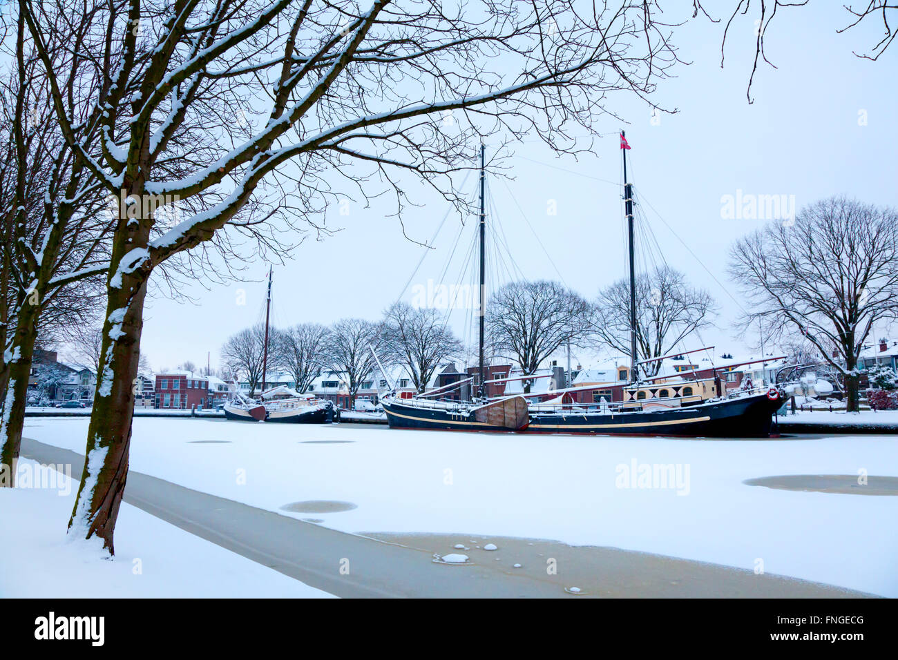 Classic boat in a frozen canal in winter in Leiden, Holland Stock Photo