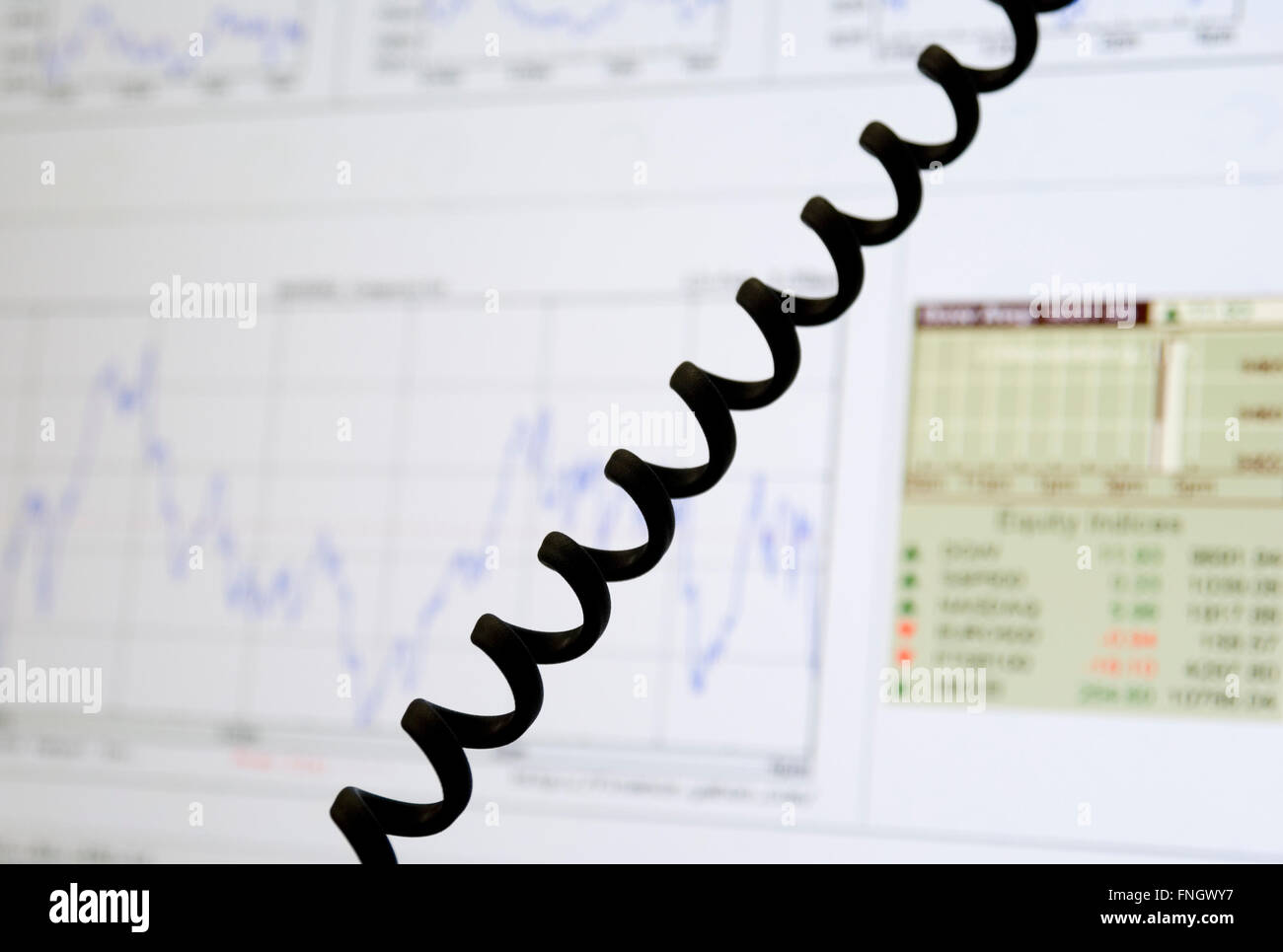 charts with financial data on monitor and telephone cable Stock Photo