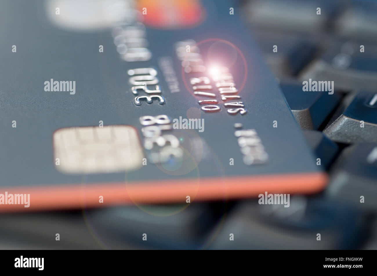 Credit card with flare effects laying on laptop's keyboard Stock Photo