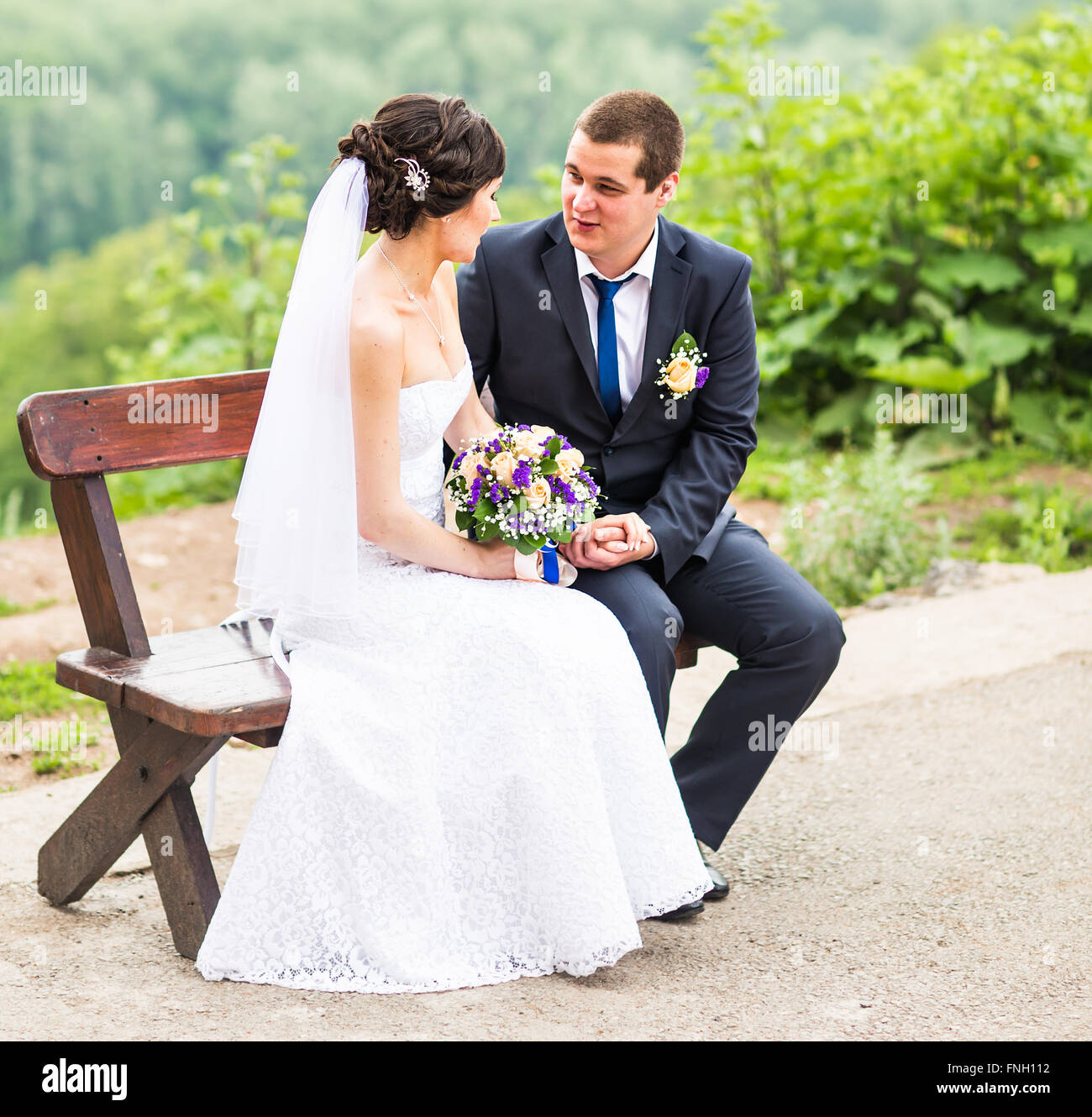 attractive bride and groom sitting on a bench Stock Photo - Alamy