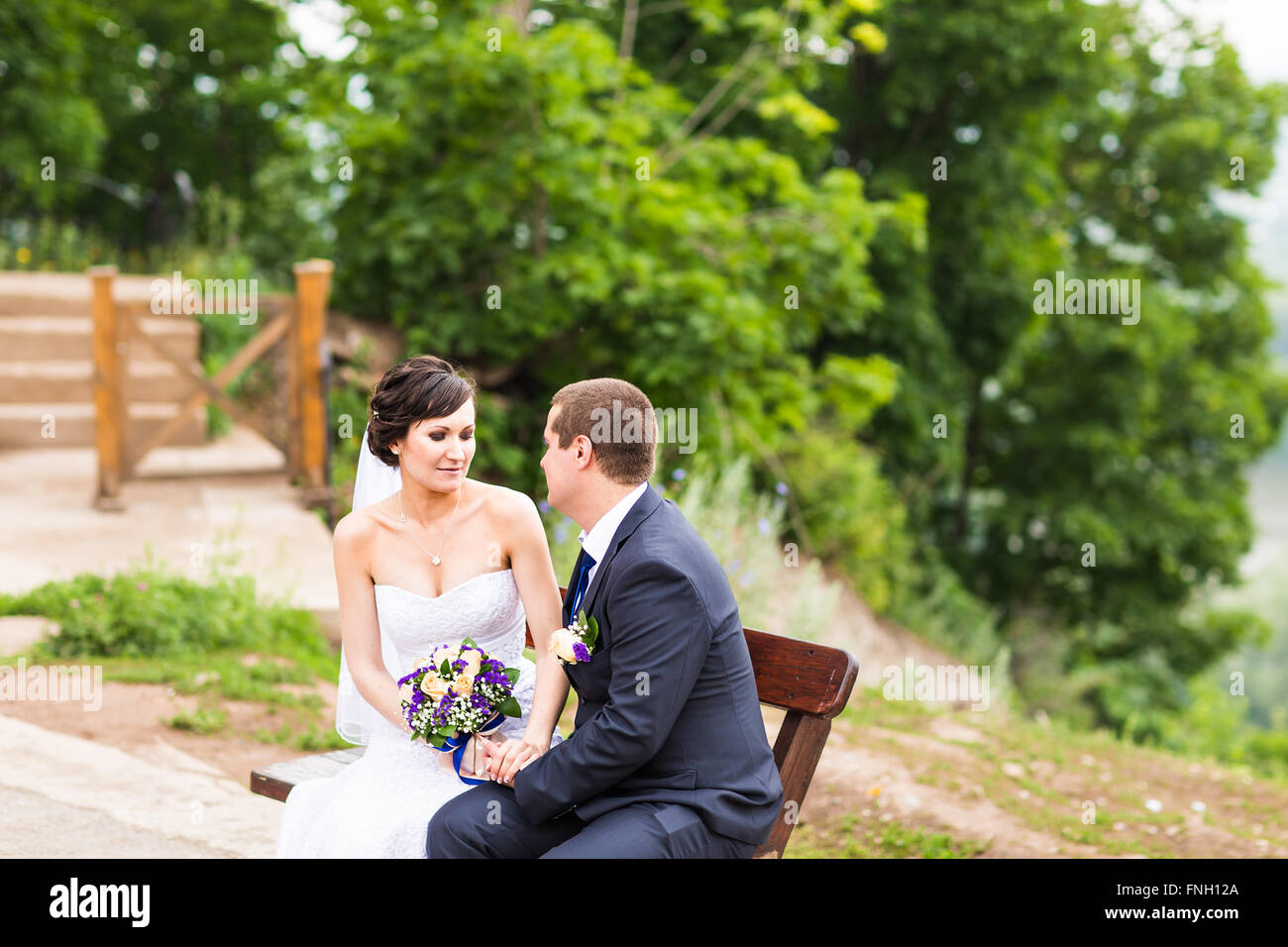 attractive bride and groom sitting on a bench Stock Photo - Alamy