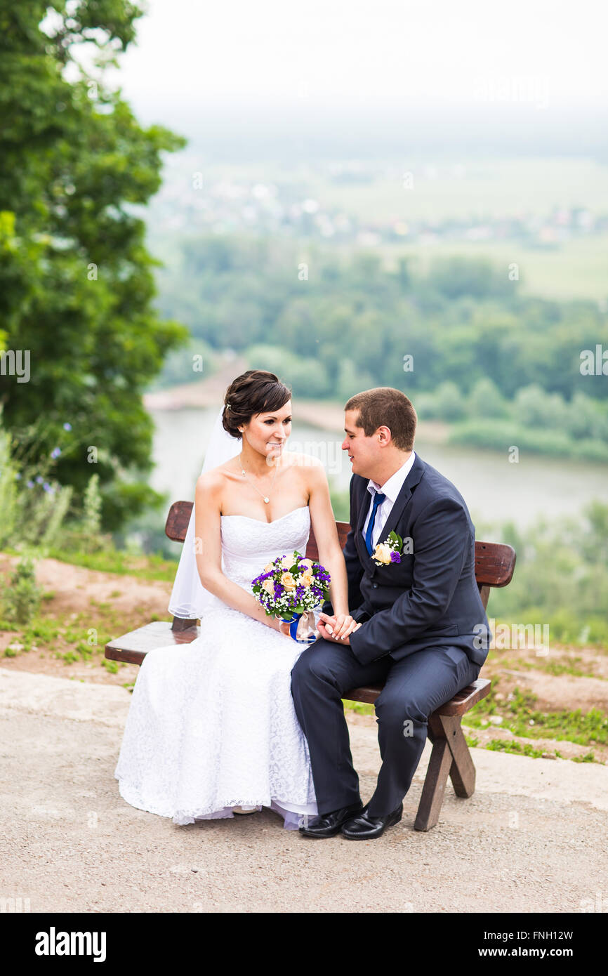 attractive bride and groom sitting on a bench Stock Photo - Alamy