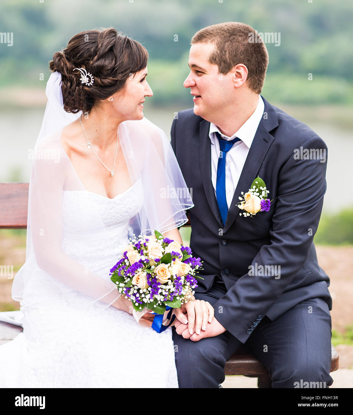 attractive bride and groom sitting on a bench Stock Photo - Alamy