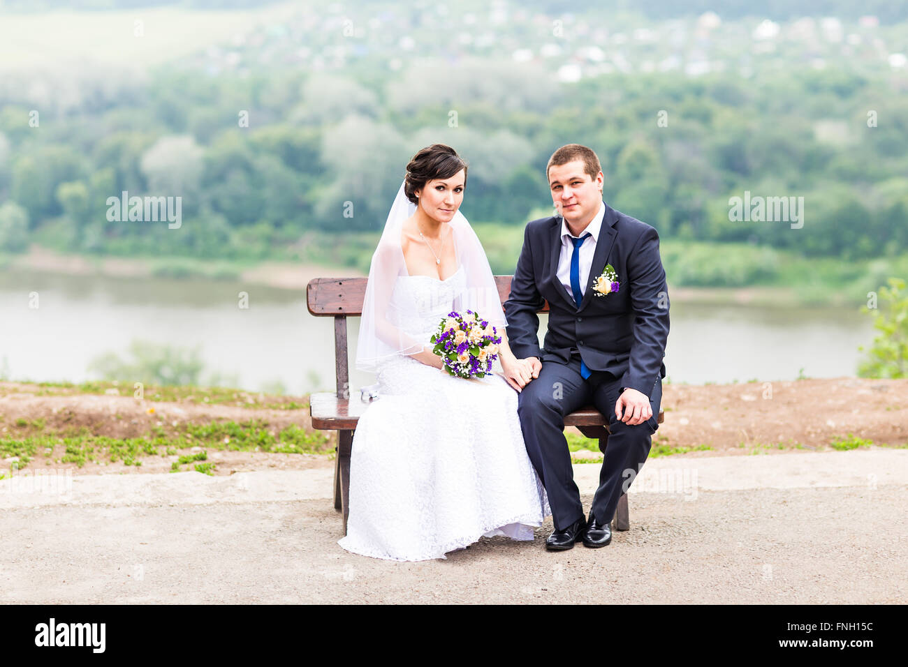 attractive bride and groom sitting on a bench Stock Photo - Alamy
