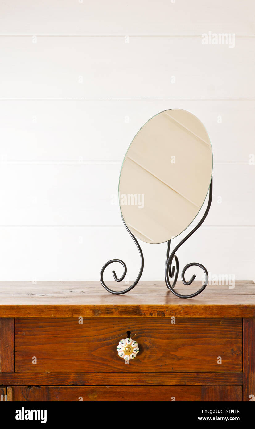 Retro mirror on bedside table,  background white wooden wall Stock Photo