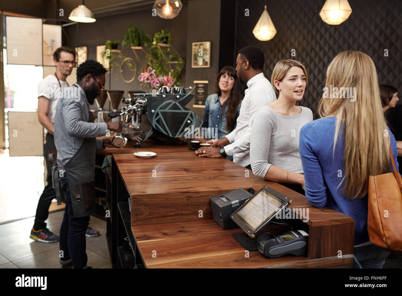 Baristas working behind counter of modern cafe busy with custome Stock Photo