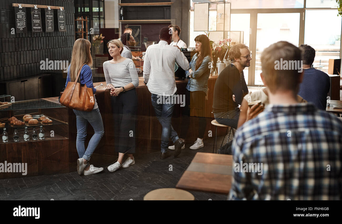 Modern coffee shop with customers standing at counter and sittin Stock Photo