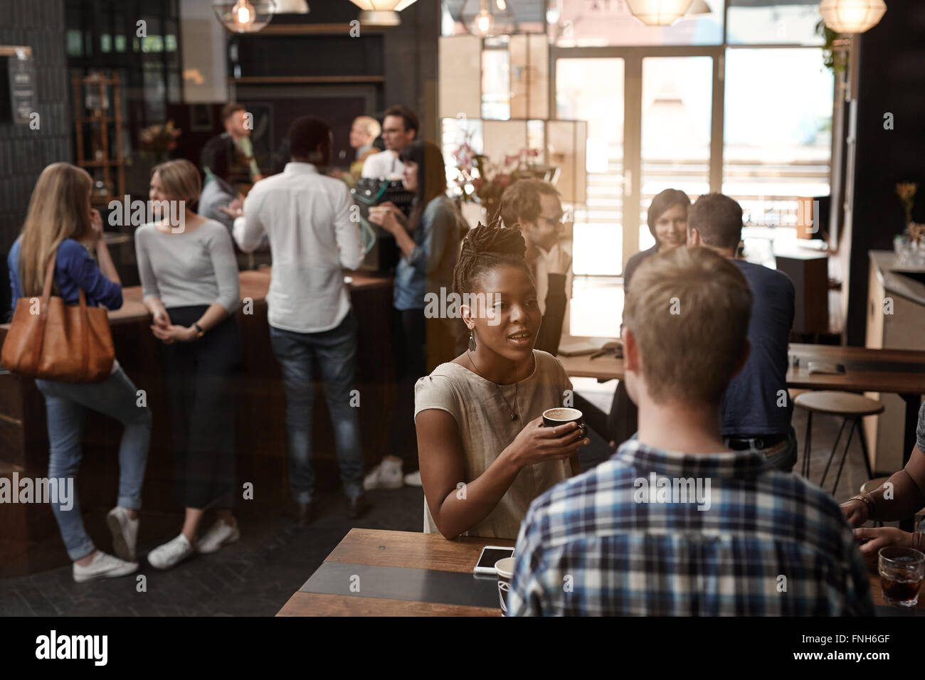 Busy coffee shop with African woman and friends talking Stock Photo