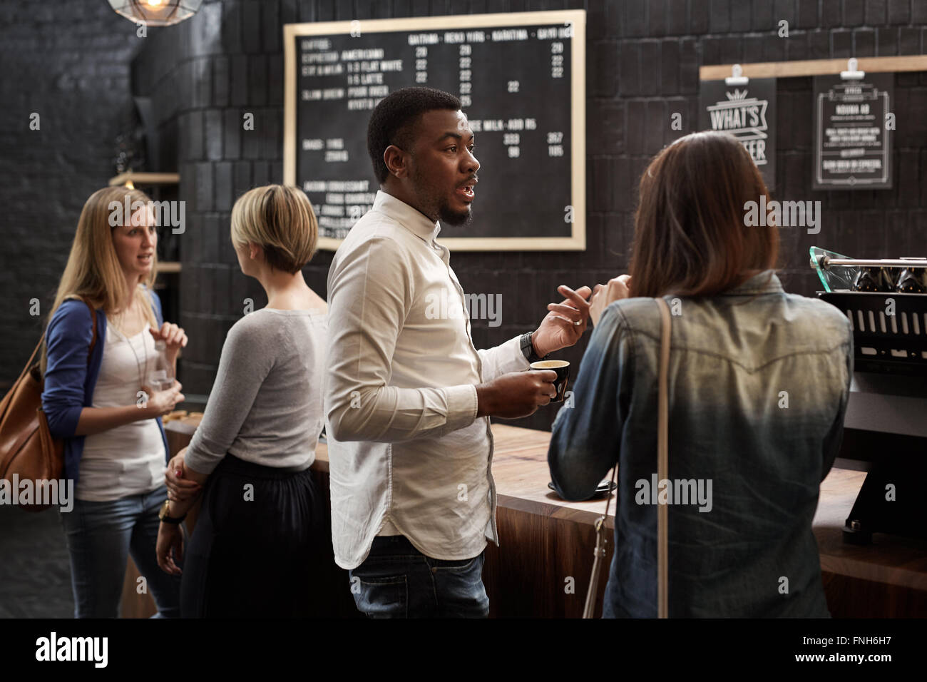 Mixed race friends talking at the counter of coffee shop Stock Photo