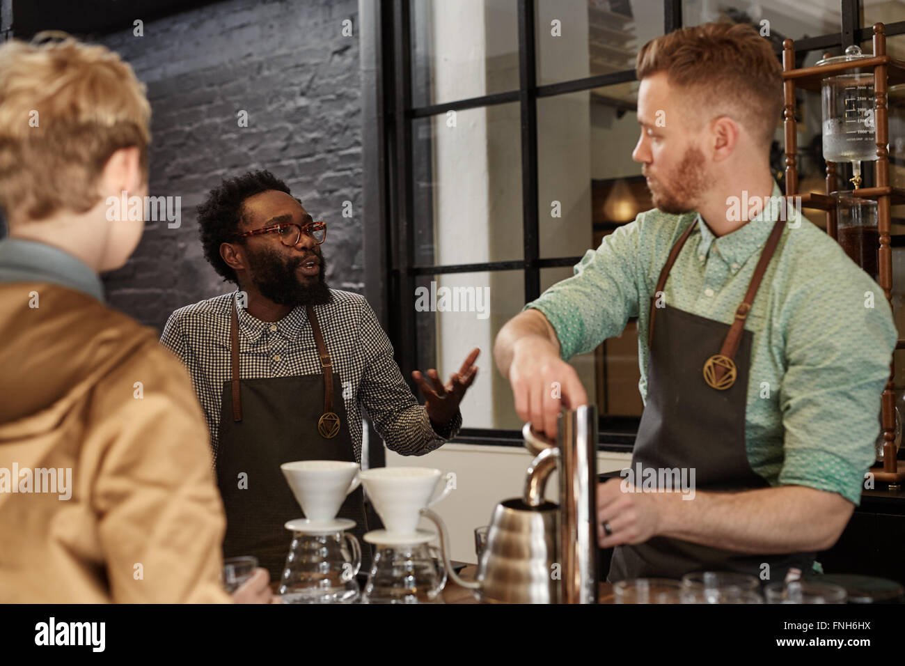 Manager explaining something to a staff member in coffee shop Stock