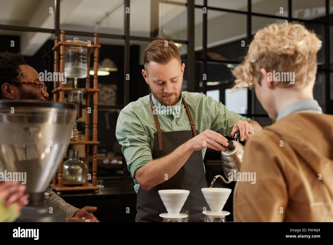 Barista pouring fresh coffee through filter in modern cafe Stock Photo