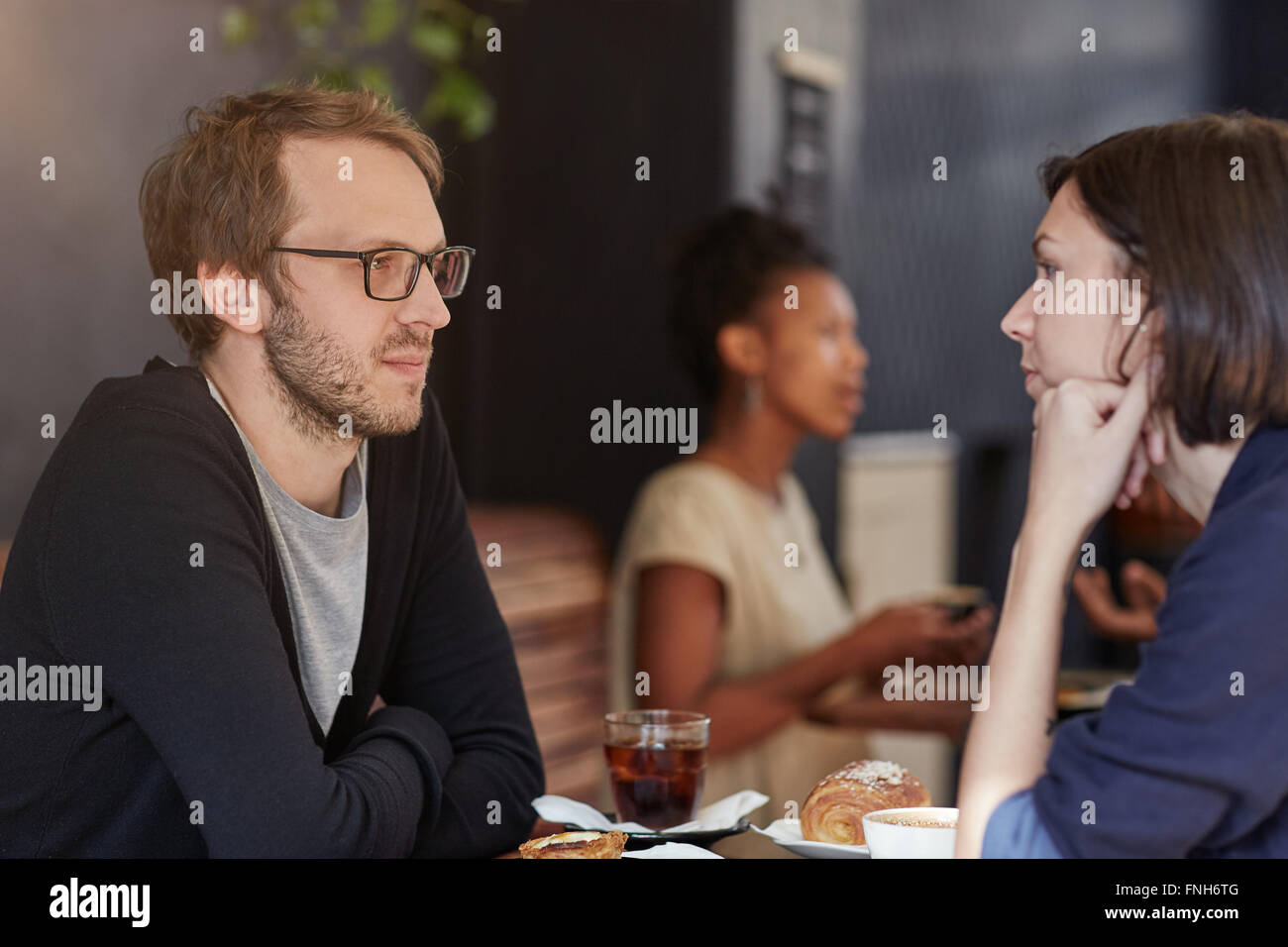 Man looking serious at a cafe table with female companion Stock Photo