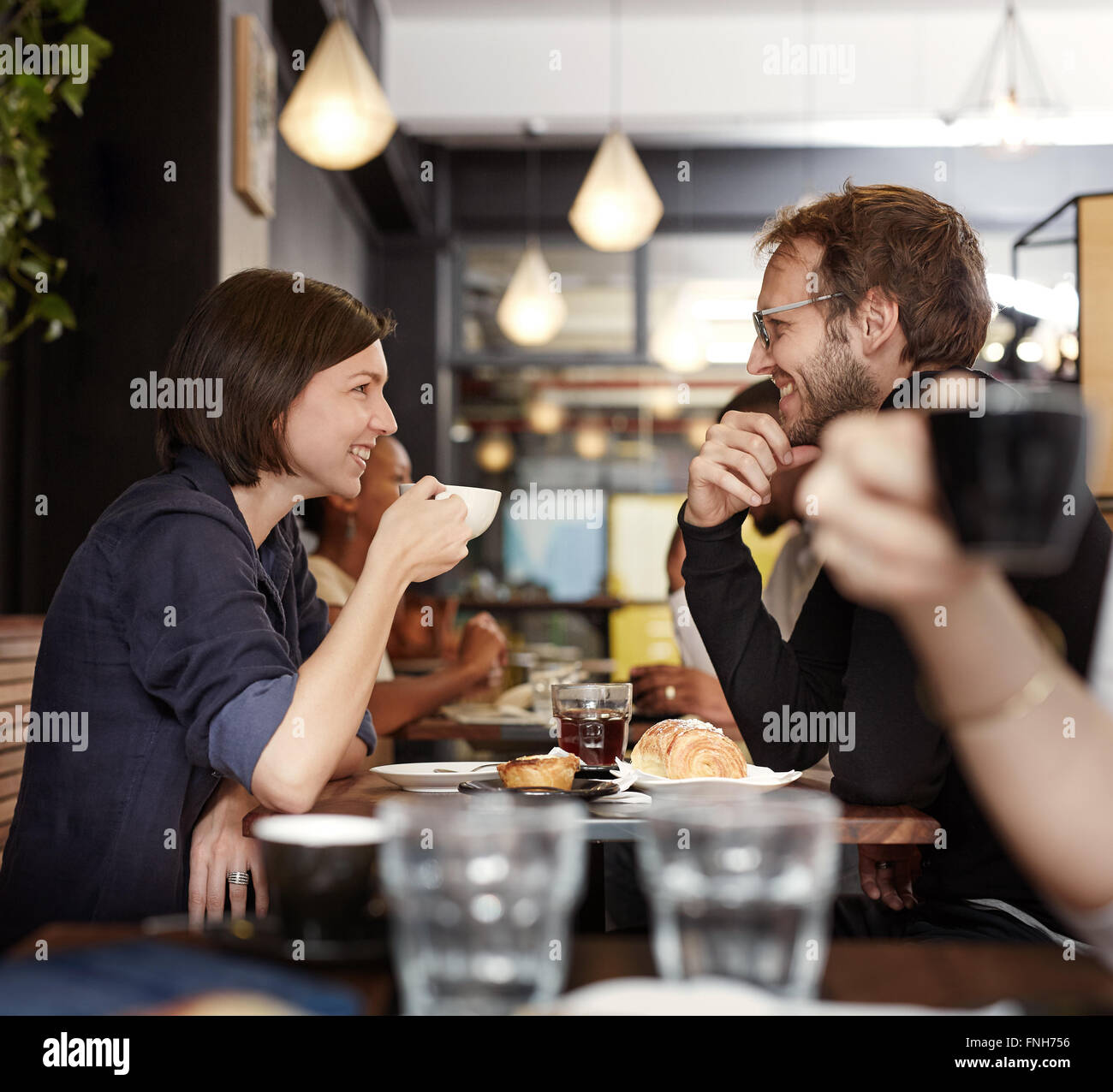 Smiling couple having coffee together in a busy cafe Stock Photo