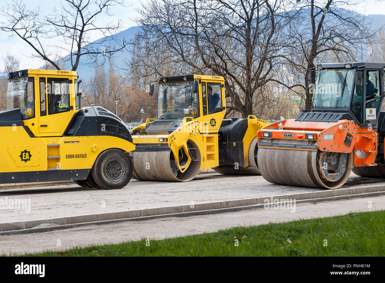 Road construction vehicles, yellow and orange road rollers Stock Photo