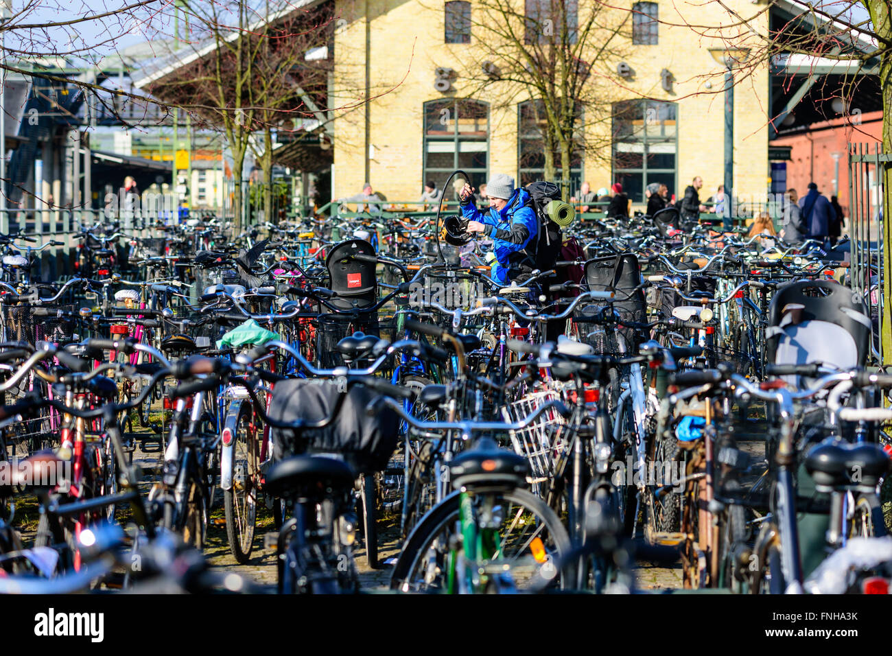 Lund, Sweden - March 12, 2016: Person with backpack standing among lots of bicycles at the bike parking lot outside the train st Stock Photo