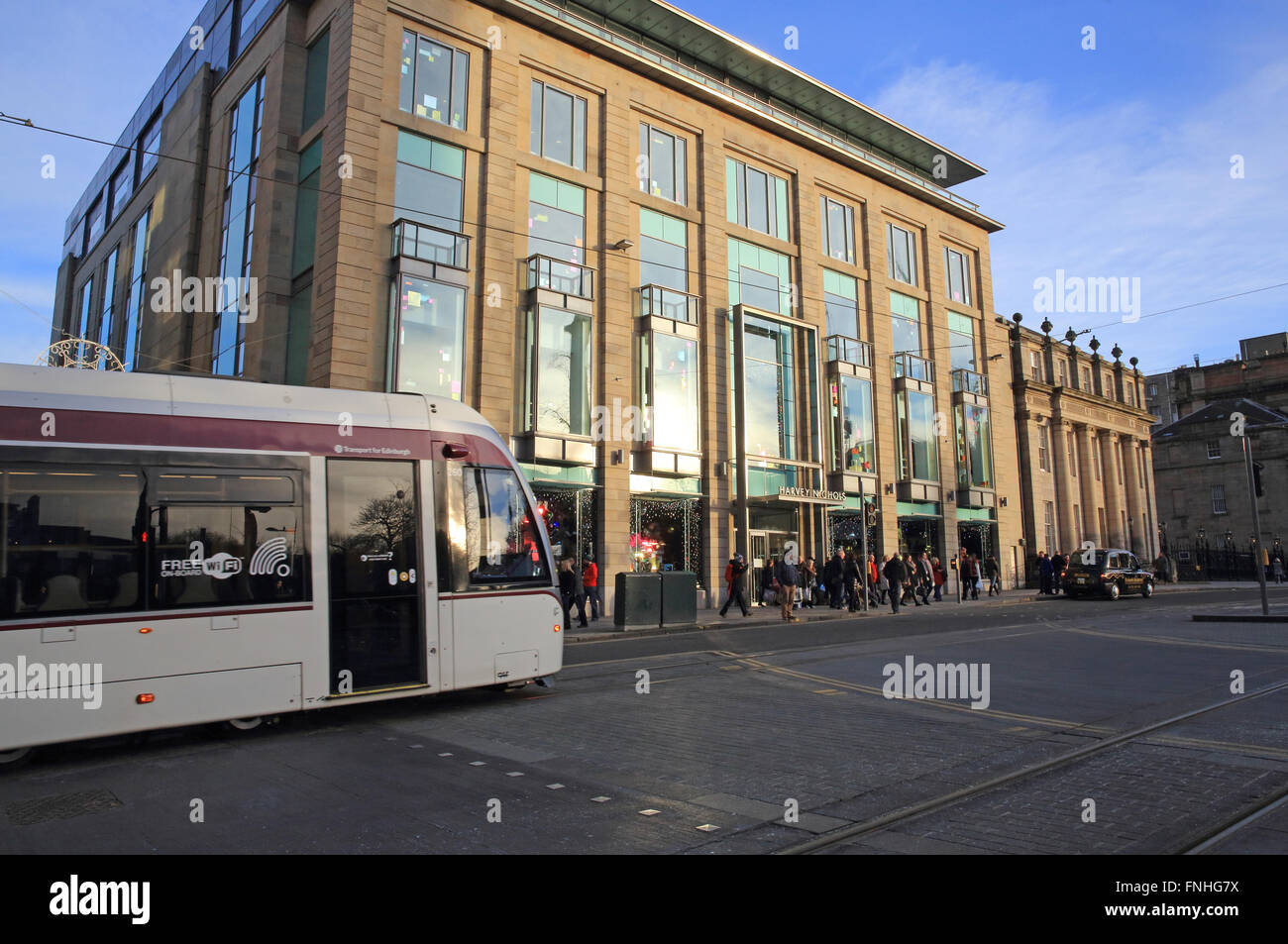 The Edinburgh tram, going past Harvey Nichols department store, on George Square in the New Town, in Scotland, UK Stock Photo