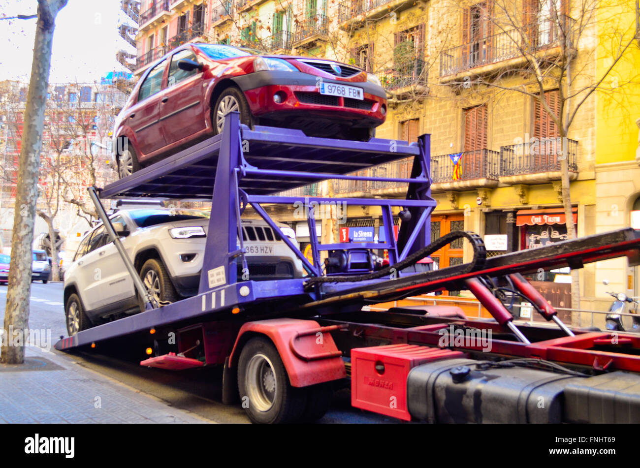 Red car carrier truck with two cars ready to download. Barcelona, Catalonia, Spain. Stock Photo